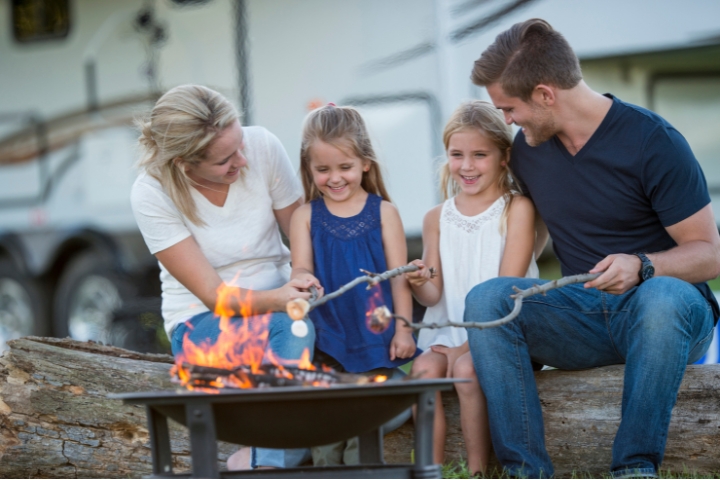 a family of four are roasting marshmallows while on a rv camping trip