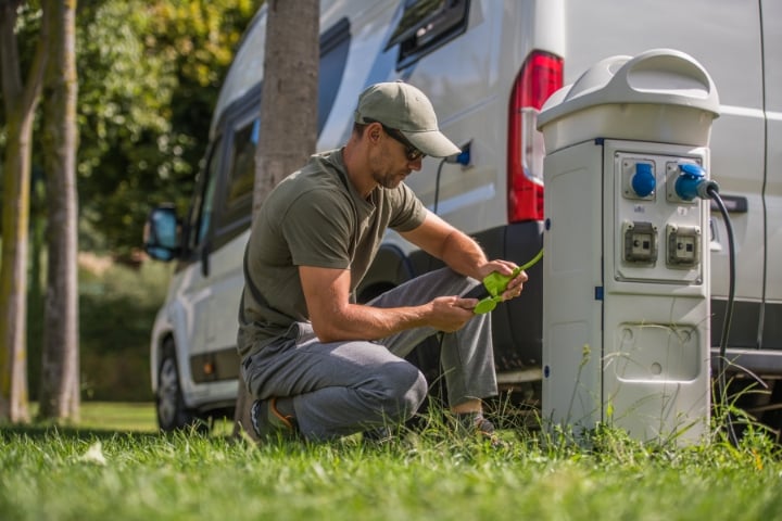 man attaching an electric plug to rv park hookup