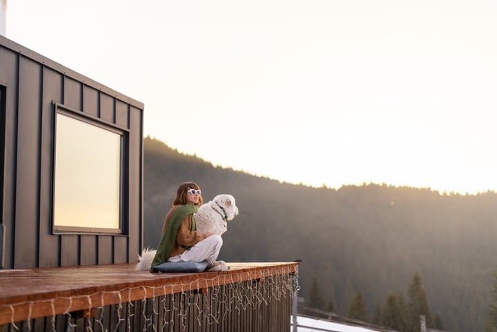 Women with her dog resting on terrace of tiny house