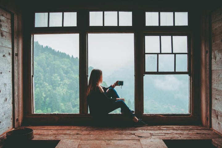 woman drinking coffee while sitting near the window