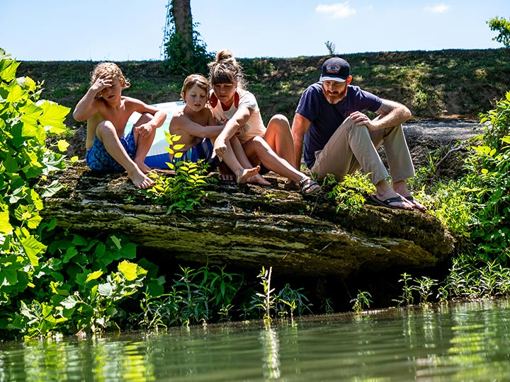 family sitting near the river