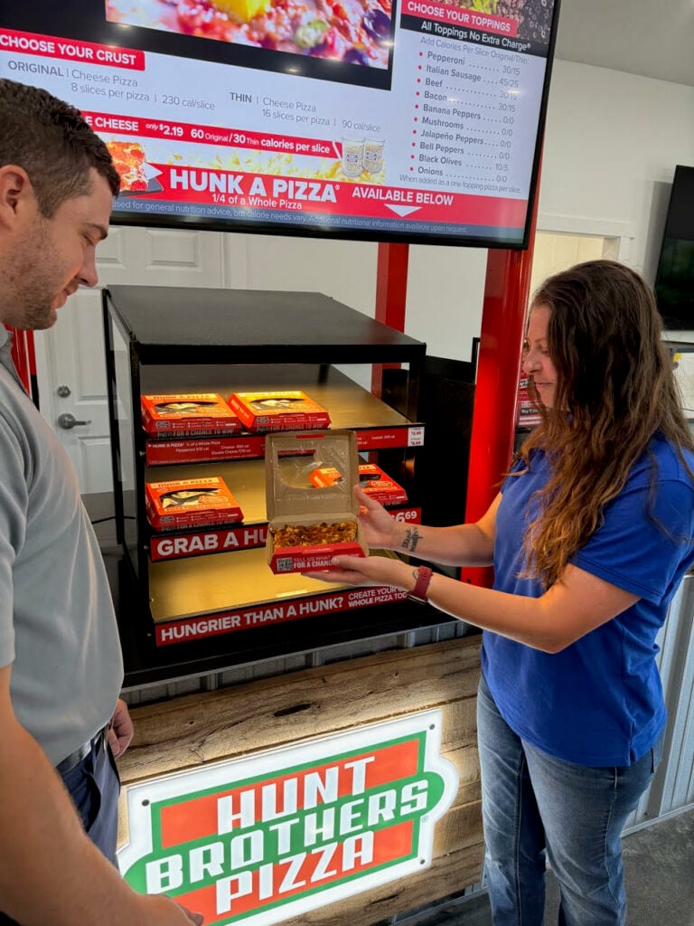 person purchasing Hunt's Brothers pizza from retail building