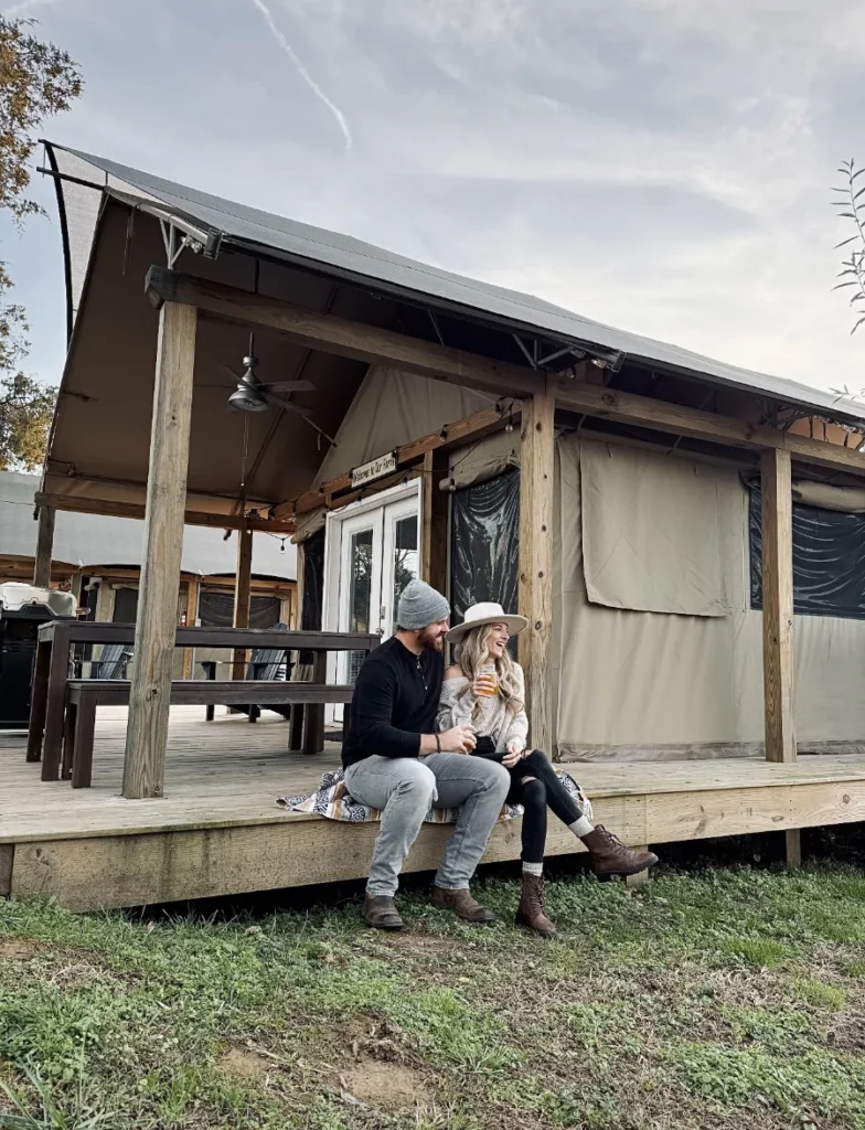 A couple sitting together outside of a glamping tent